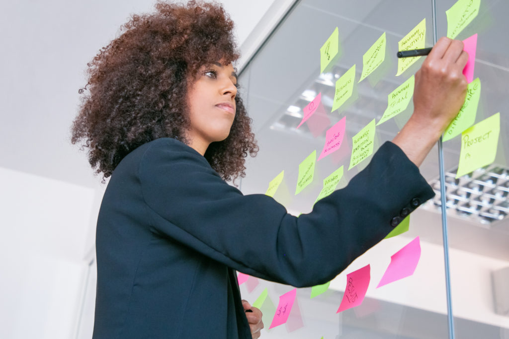 Mulher-de-negócios-praticando-a-produtividade-empreendedora-escrevendo-em-etiquetas-com-marcador